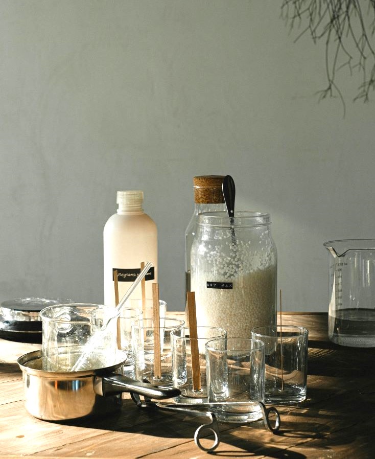 木のテーブルの上に並んだ手作りのスキンケア用品やガラス瓶、計量カップ
