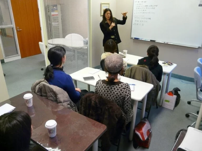 カナダ・バンクーバーのオフィスで、留学生やワーキングホリデーの若者に向けたキャリア支援セミナーを行い、ホワイトボードの前で熱心に講義をしている様子。